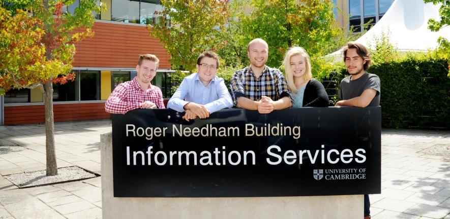 UIS staff members stand behind the Information Services sign outside the Roger Needham Building